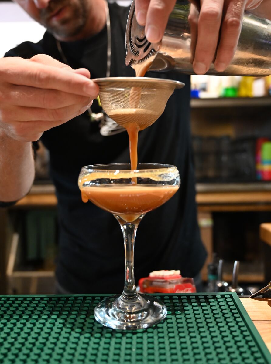 A bartender filters out the parts of a cocktail indoors.